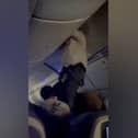 Passengers help man from overhead bin after 'strong turbulence'.